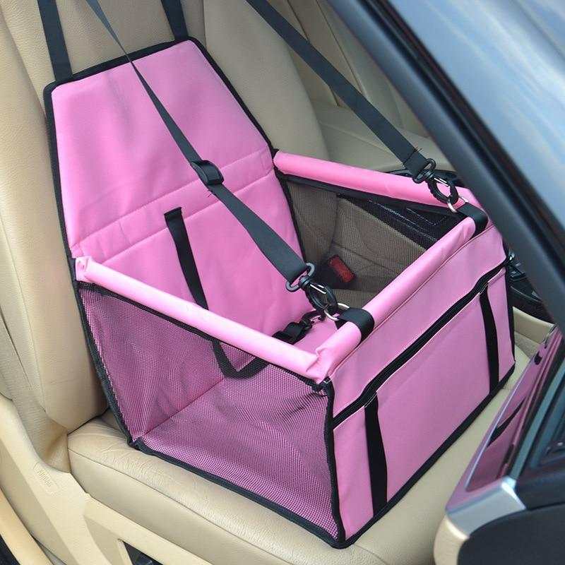 Pink dog travel car seat carrier with adjustable straps and mesh sides securely installed in beige car seat