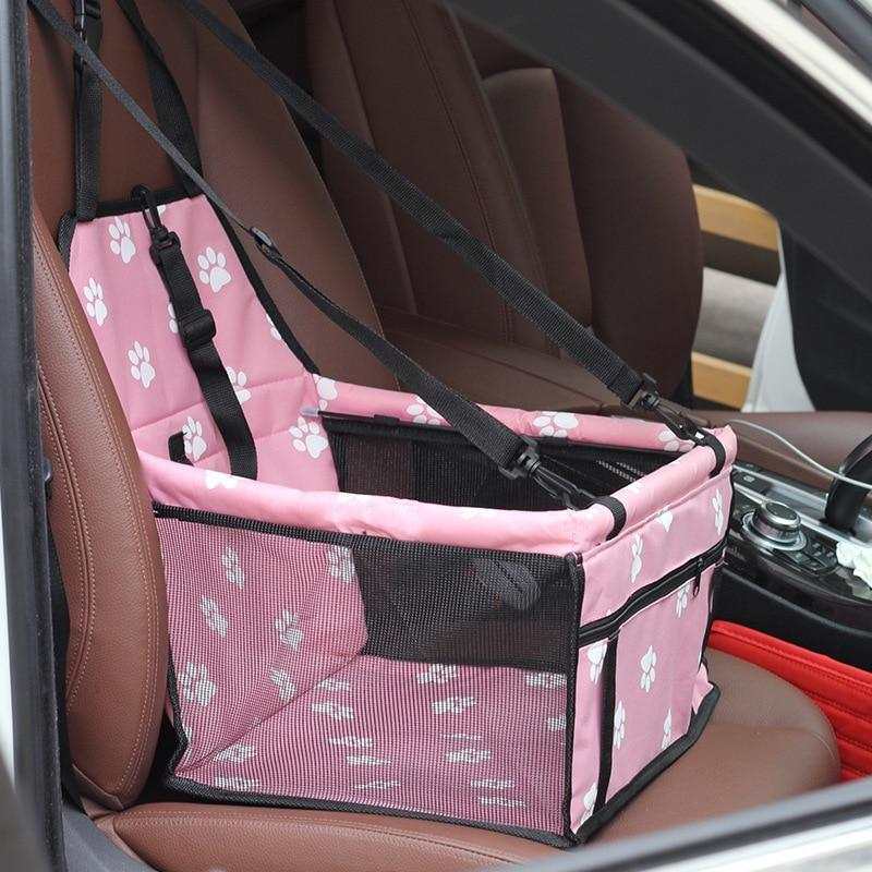 Pink pet car hammock with paw print design and adjustable safety straps securely attached to car seat