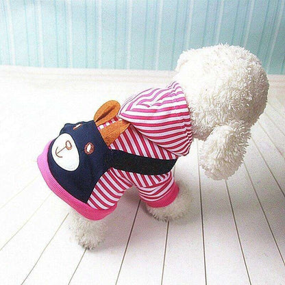 Small white dog wearing a pink and white striped dog hoodie with bear face design.