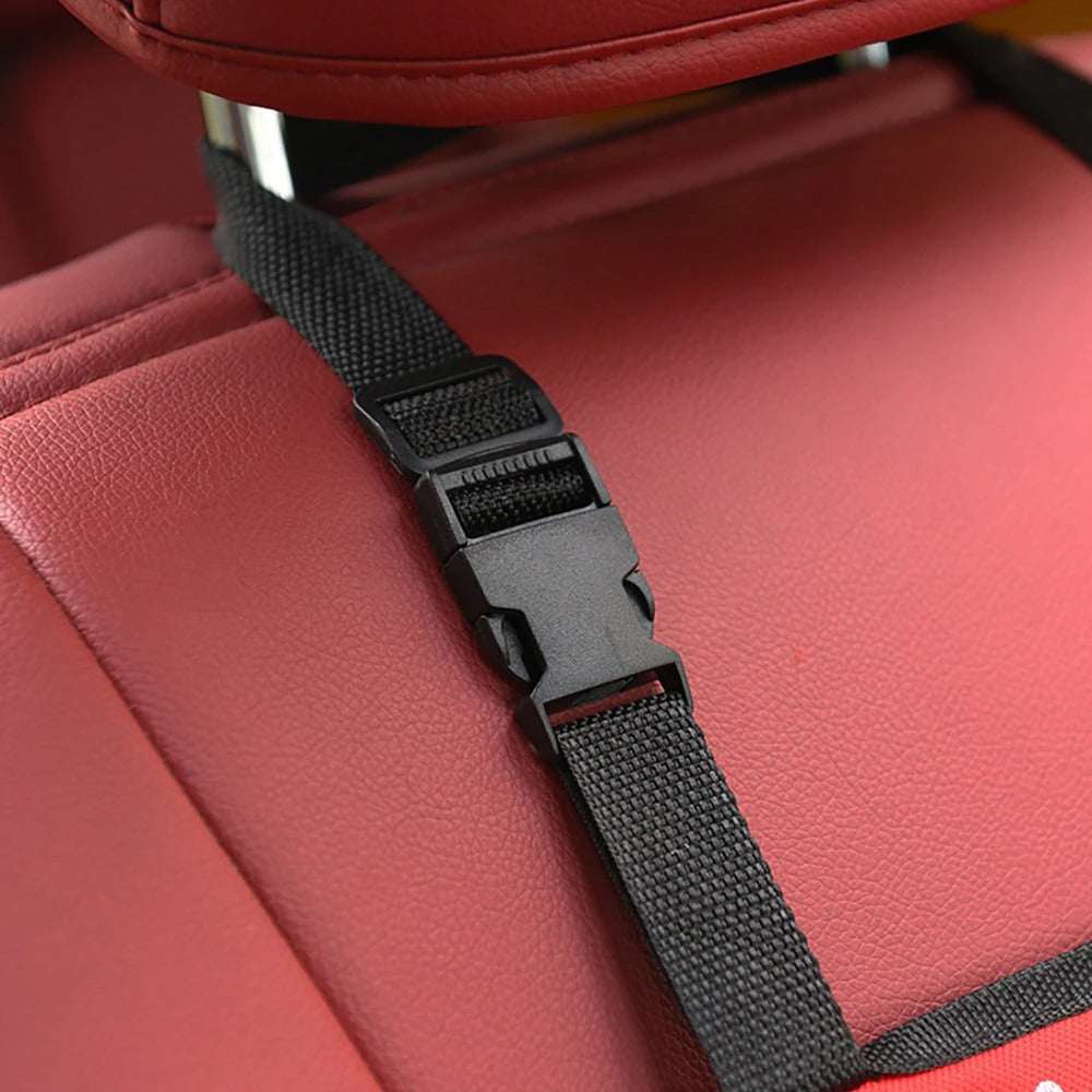Adjustable black buckle strap securing pet car hammock on red car seat headrest