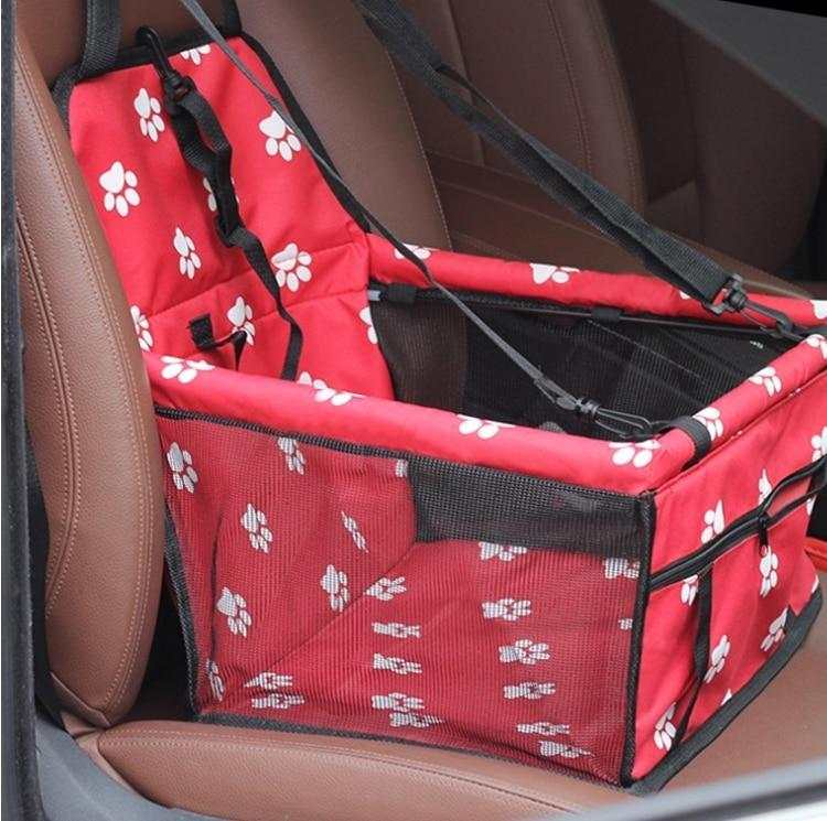 Red foldable pet car hammock with white paw prints securely installed on a brown car seat