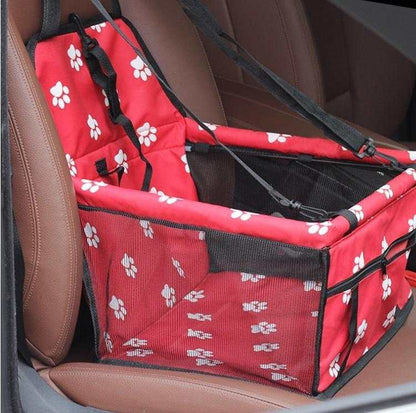 Red foldable pet car hammock with white paw prints securely installed on a brown car seat